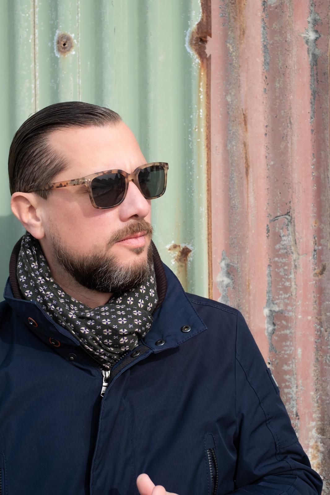 Paul Baptista with sunglasses in front of a corrugated metal wall.